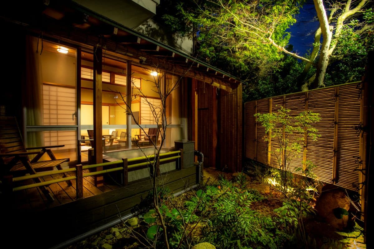 Arima Gyoen guest room exterior at night with warm lantern light, wooden deck and an illuminated garden