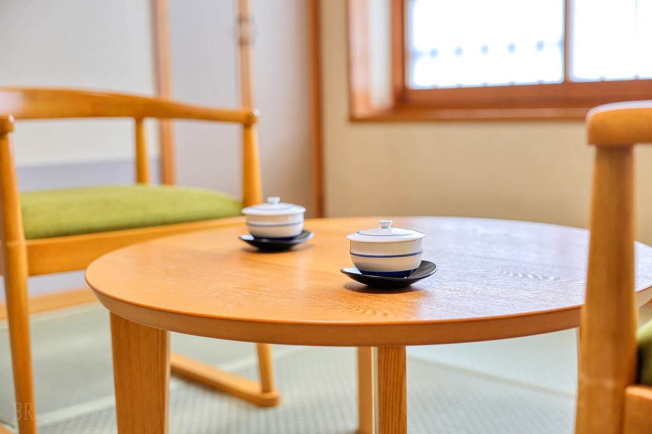 Detail of a tatami guest room at Hotel Asafuji with a round wooden table set with lidded teacups