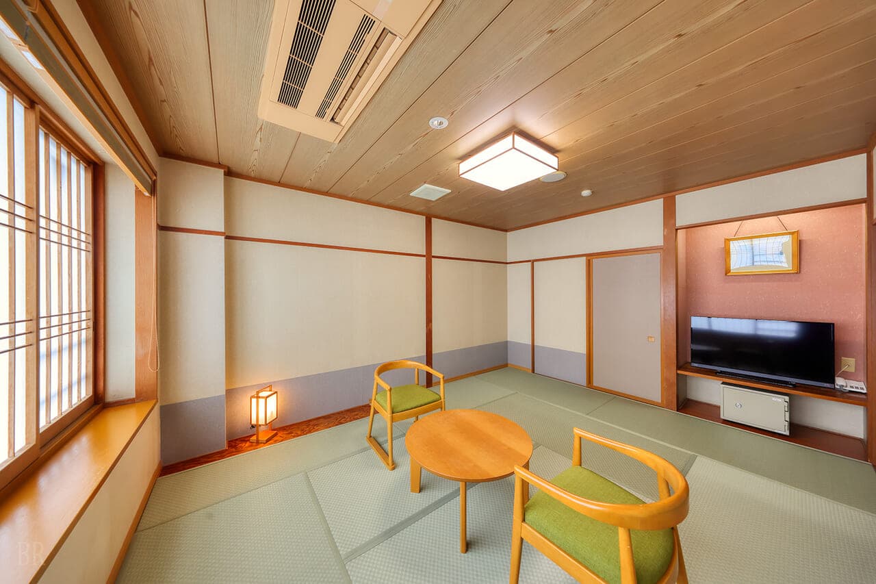 Bright wide-angle tatami guest room at Hotel Asafuji with wooden chairs, a lantern and a flat-screen television
