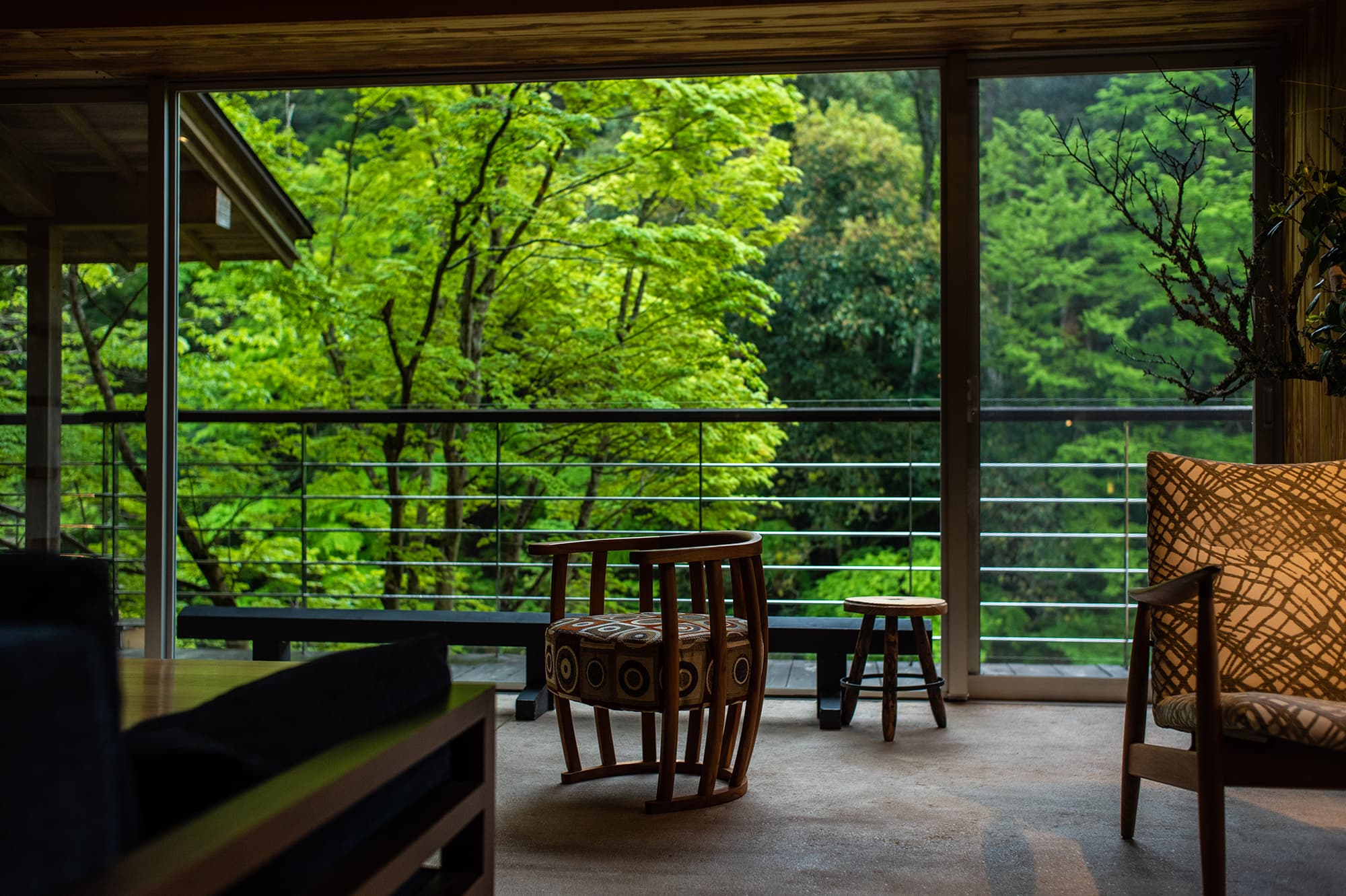 Quiet balcony lounge nook at Asebino with a low table and chairs opening onto the riverside maples, Yugashima Onsen Izu