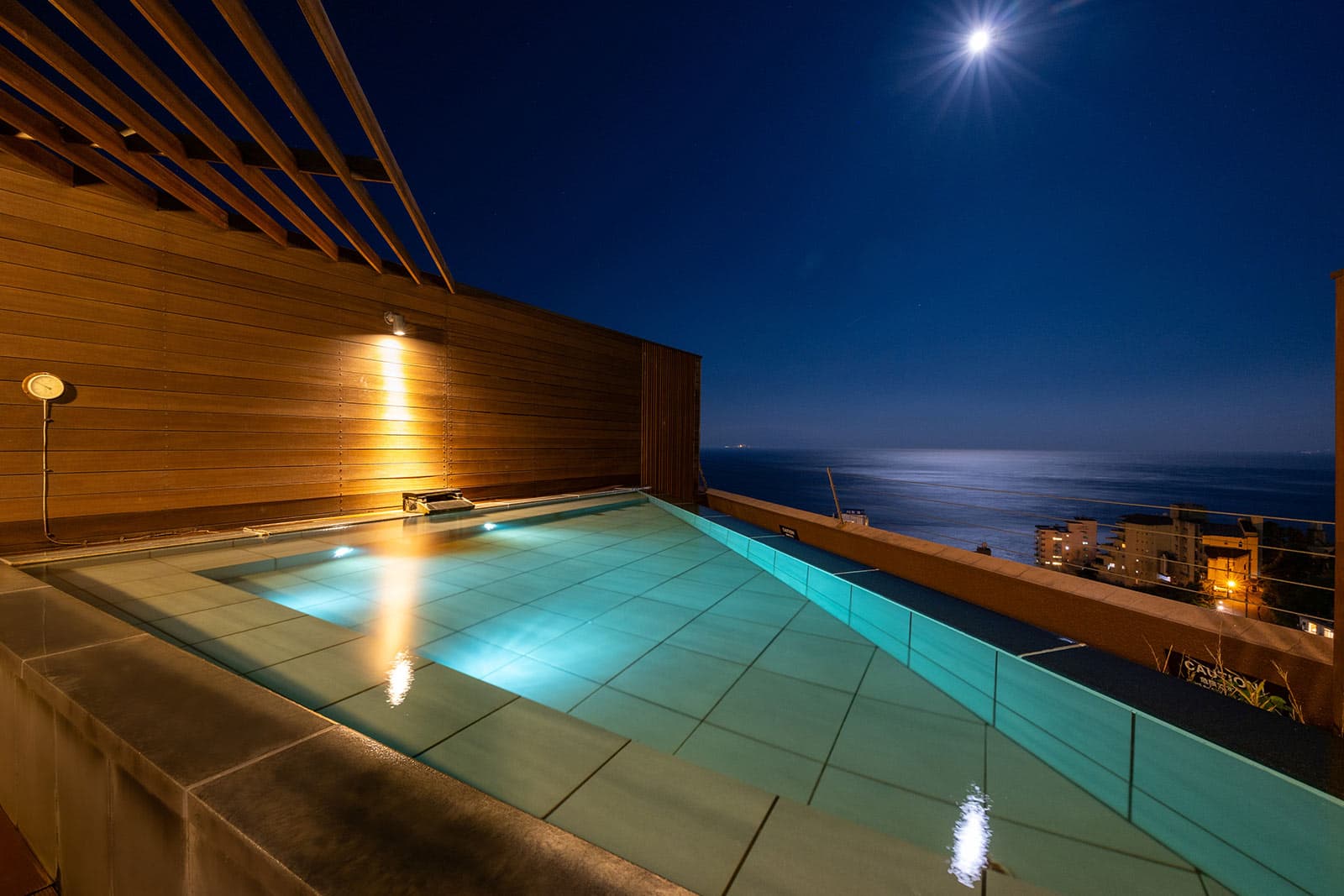 Illuminated rooftop infinity pool overlooking the moonlit ocean at night, Atagawa Prince Hotel, Izu