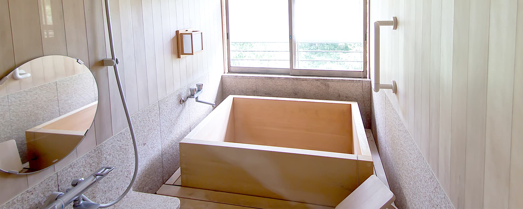 Private indoor hinoki wood bath with a window framing greenery at Atami Taikanso in Atami Onsen