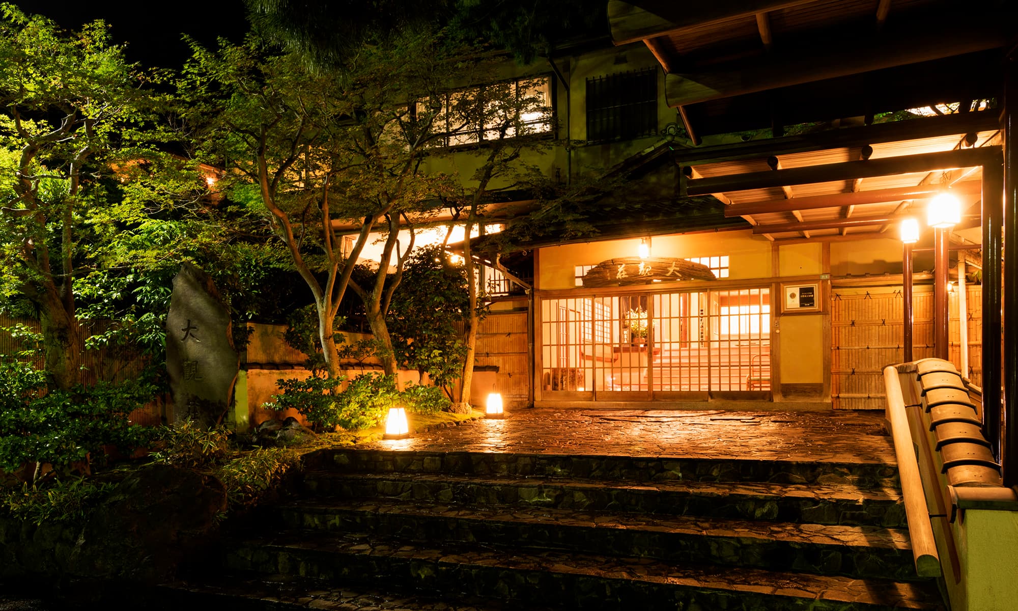 Atami Taikanso traditional entrance and stone steps lit by lanterns at night in Atami Onsen