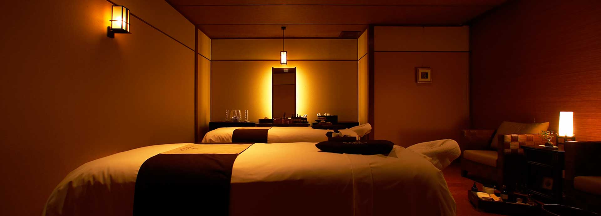 Twin treatment beds in the warmly lit spa room at Bousui with lanterns and a calm Japanese interior
