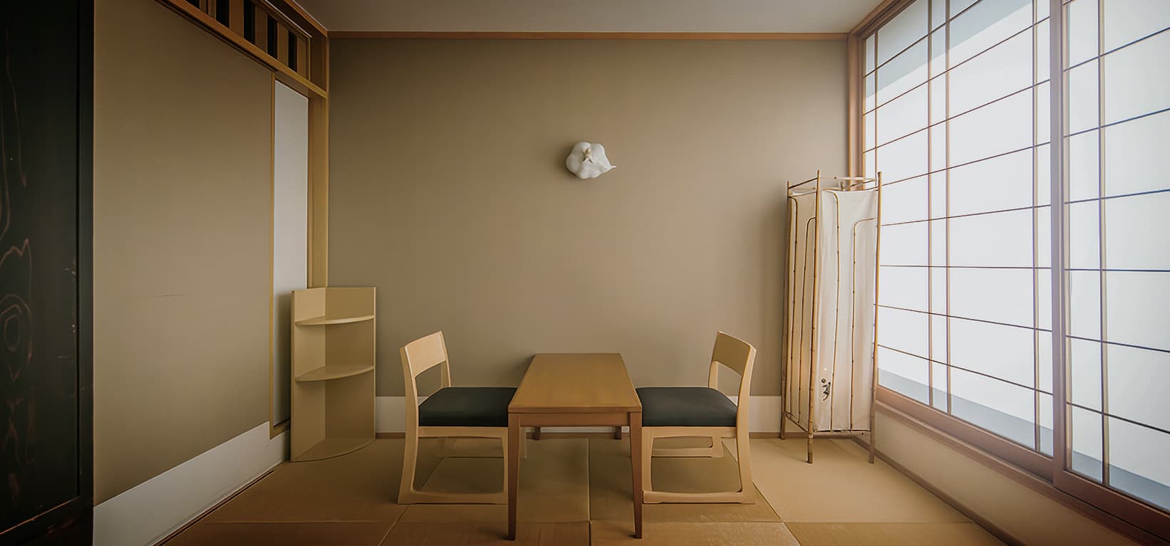 Quiet tatami sitting nook with low chairs and bright shoji windows at a Dogo Yumekura villa