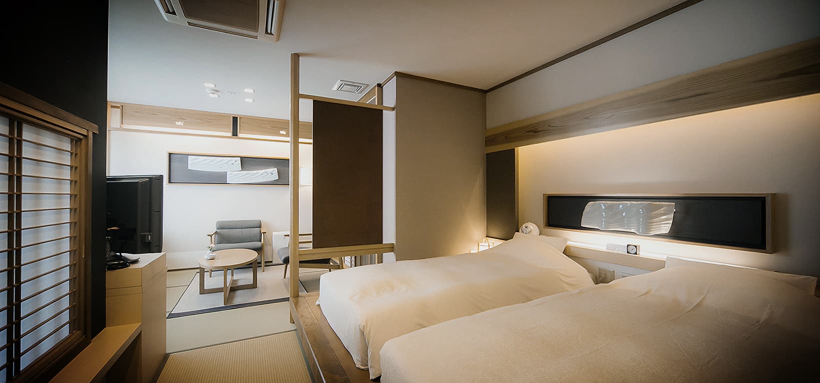 Minimalist modern Japanese twin bedroom with indirect lighting and wood paneling at a Dogo Yumekura villa