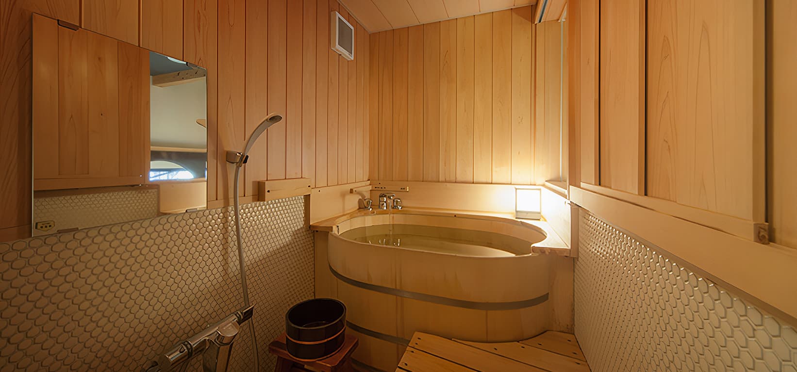 Oval hinoki cypress soaking tub in a wood-paneled private bathroom at a Dogo Yumekura maisonette villa