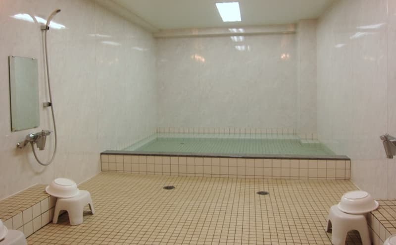 Large shared bath in the basement of Sakuraya with a tiled tub and washing stations