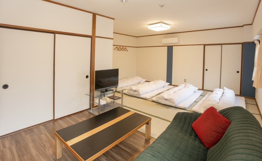 Mountain-side room at Sakuraya with futons on tatami, a low table and a sofa