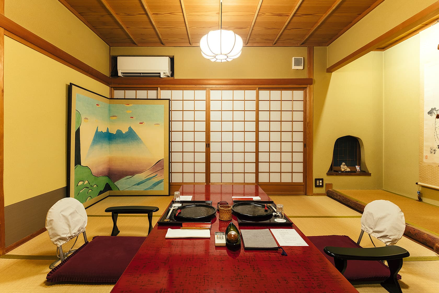 Private tatami dining room at Daimaru Besso set with sukiyaki ironware, a painted folding screen and a hanging lantern