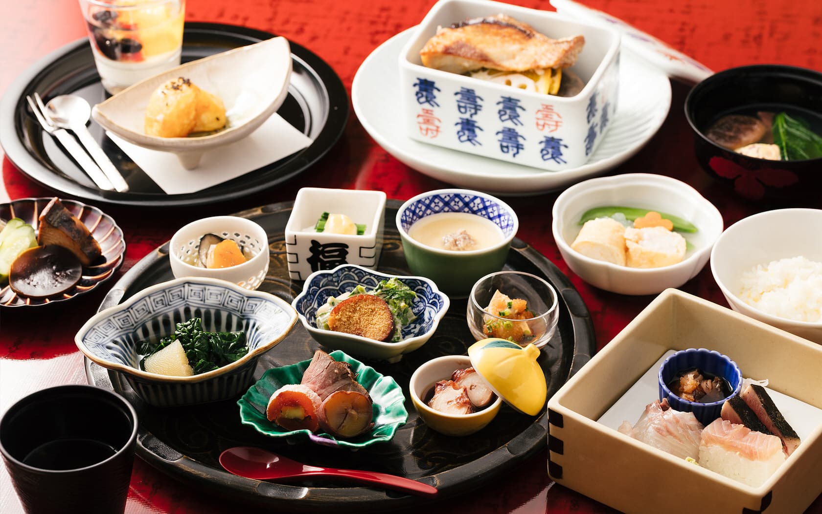Kaiseki dinner spread at Daimaru Besso with assorted small dishes, grilled fish and rice on a black lacquer tray