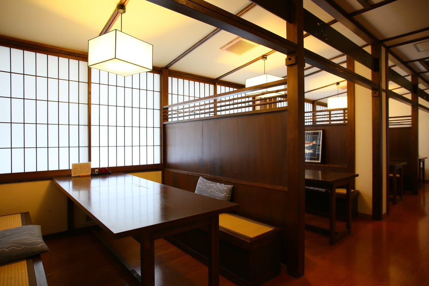 Wood-beamed private dining alcoves with shoji windows and lantern lighting at Shirahone Ebisuya