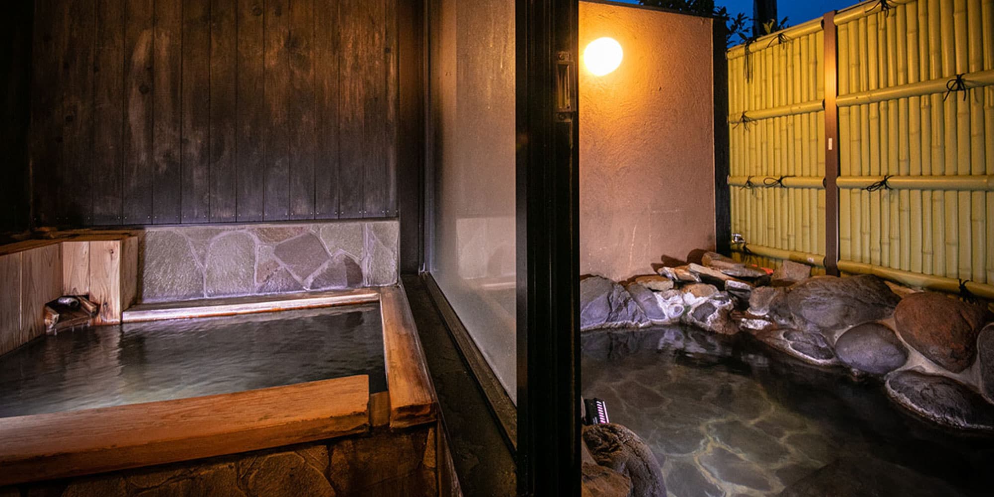 Private guest-room bath with indoor wooden tub and outdoor stone rotenburo behind a bamboo fence at Kazenomori
