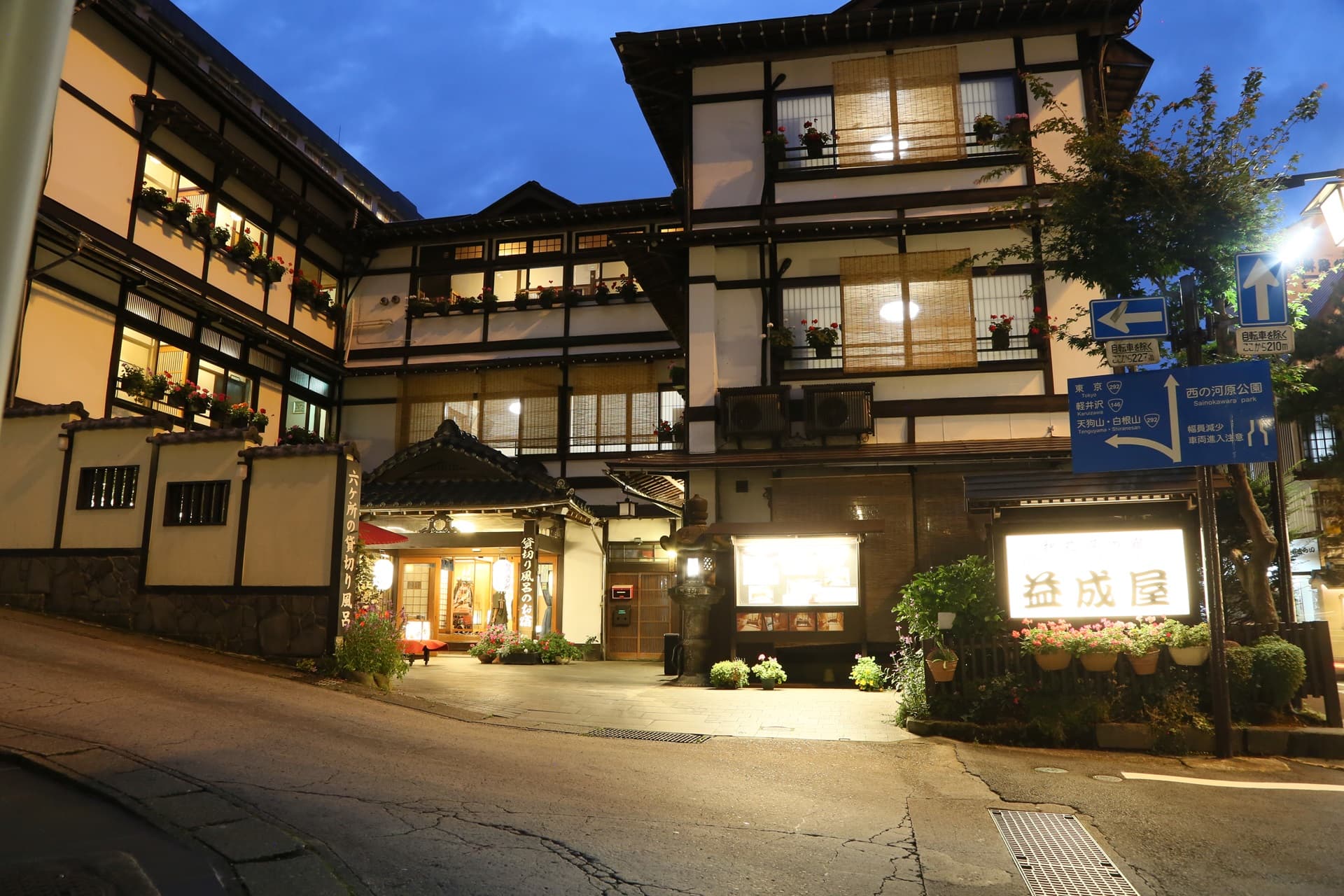 Ekinariya Ryokan traditional multi-storey wooden building lit at dusk with on-site signage, Kusatsu Onsen