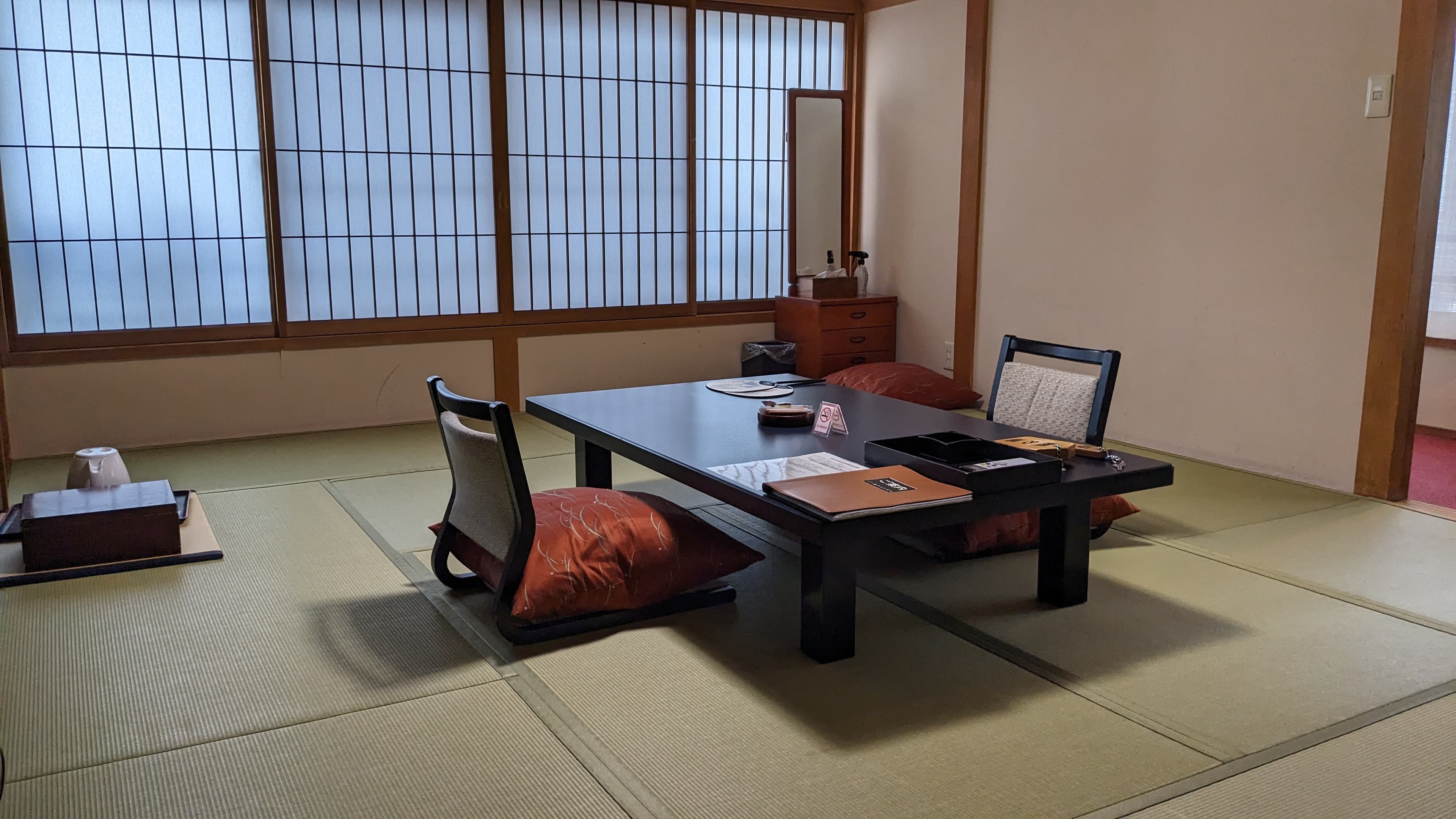 Ten-tatami Japanese guest room at Ekinariya Ryokan with shoji screens, low lacquered table and floor chairs
