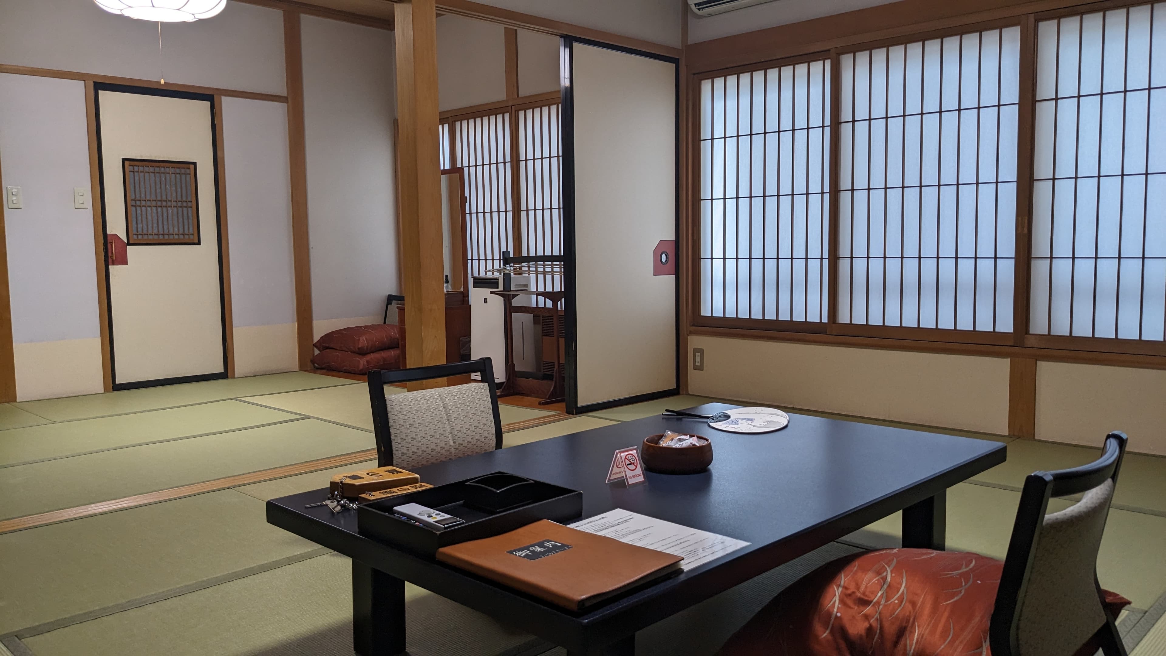 Spacious twelve-tatami guest room at Ekinariya Ryokan with shoji windows and traditional decorative transom