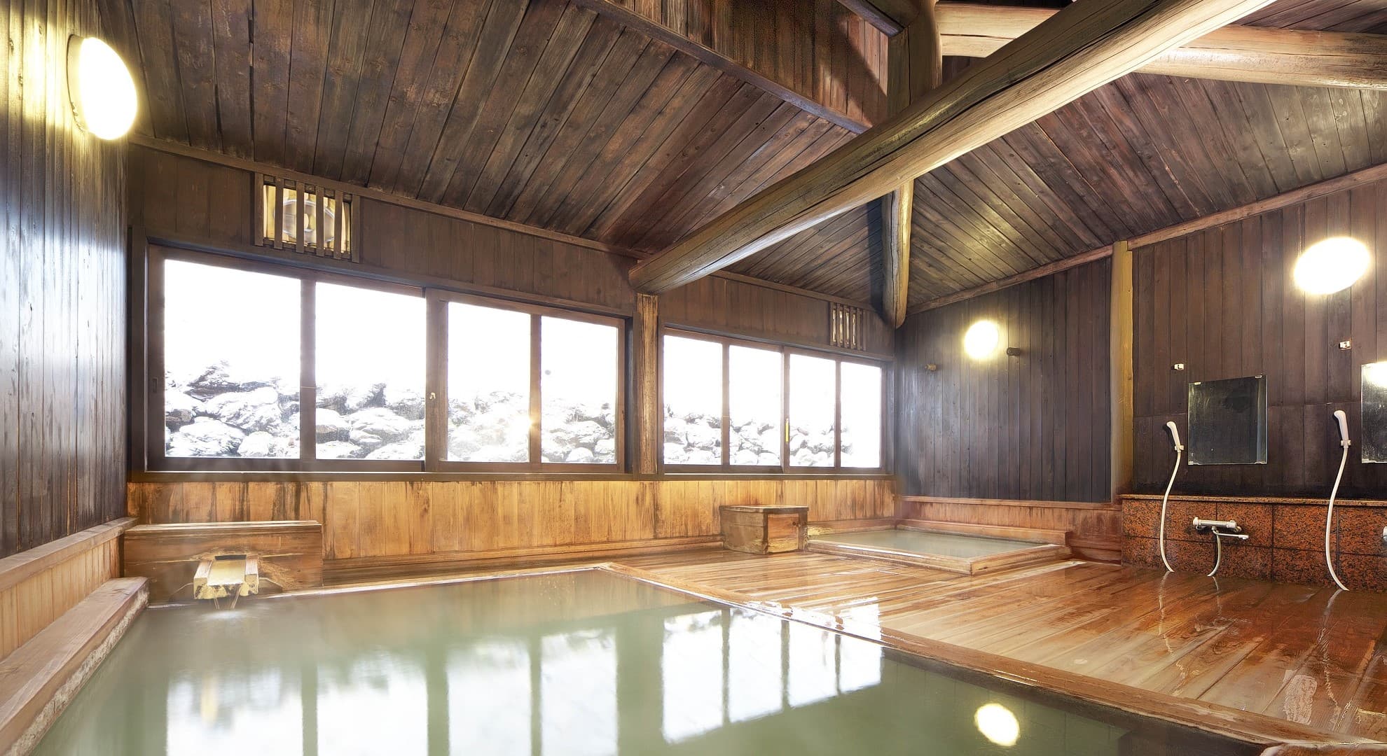 Indoor wooden hot-spring bath at Ekinariya Ryokan filled with milky sulphur water under a timber-beamed ceiling