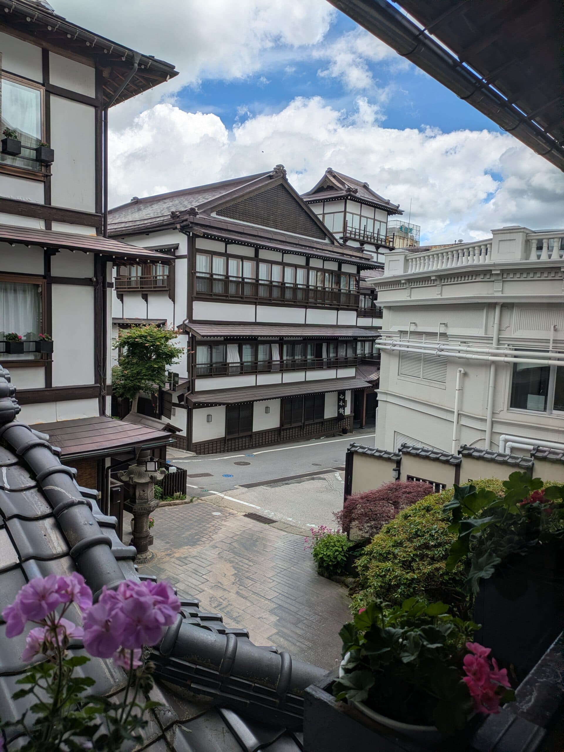 Ekinariya Ryokan's traditional wooden facade seen from a balcony with hydrangea flowers in the foreground, Kusatsu Onsen old town