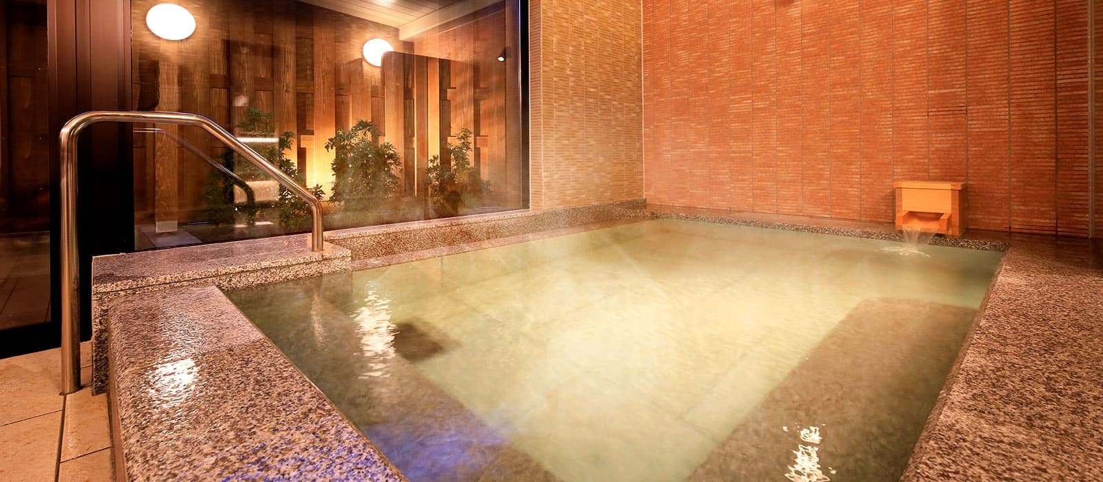 Indoor public stone bath with steaming hot-spring water and warm lighting