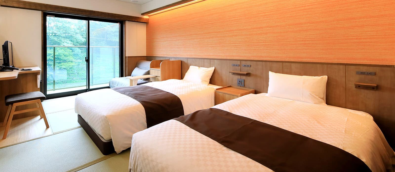 Twin guest room with warm wood walls and large window overlooking greenery