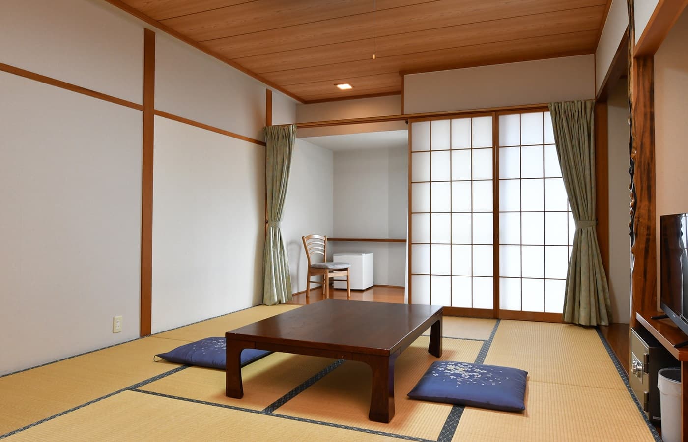 Bright tatami guest room at Hakuba Marukin Ryokan with low table, floor cushions and shoji-screen sliding doors
