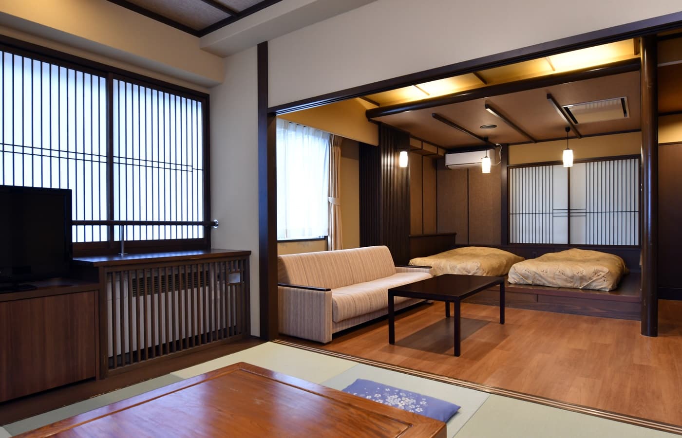 Spacious Japanese-Western guest room at Hakuba Marukin Ryokan with tatami sitting area, sofa and twin futon beds