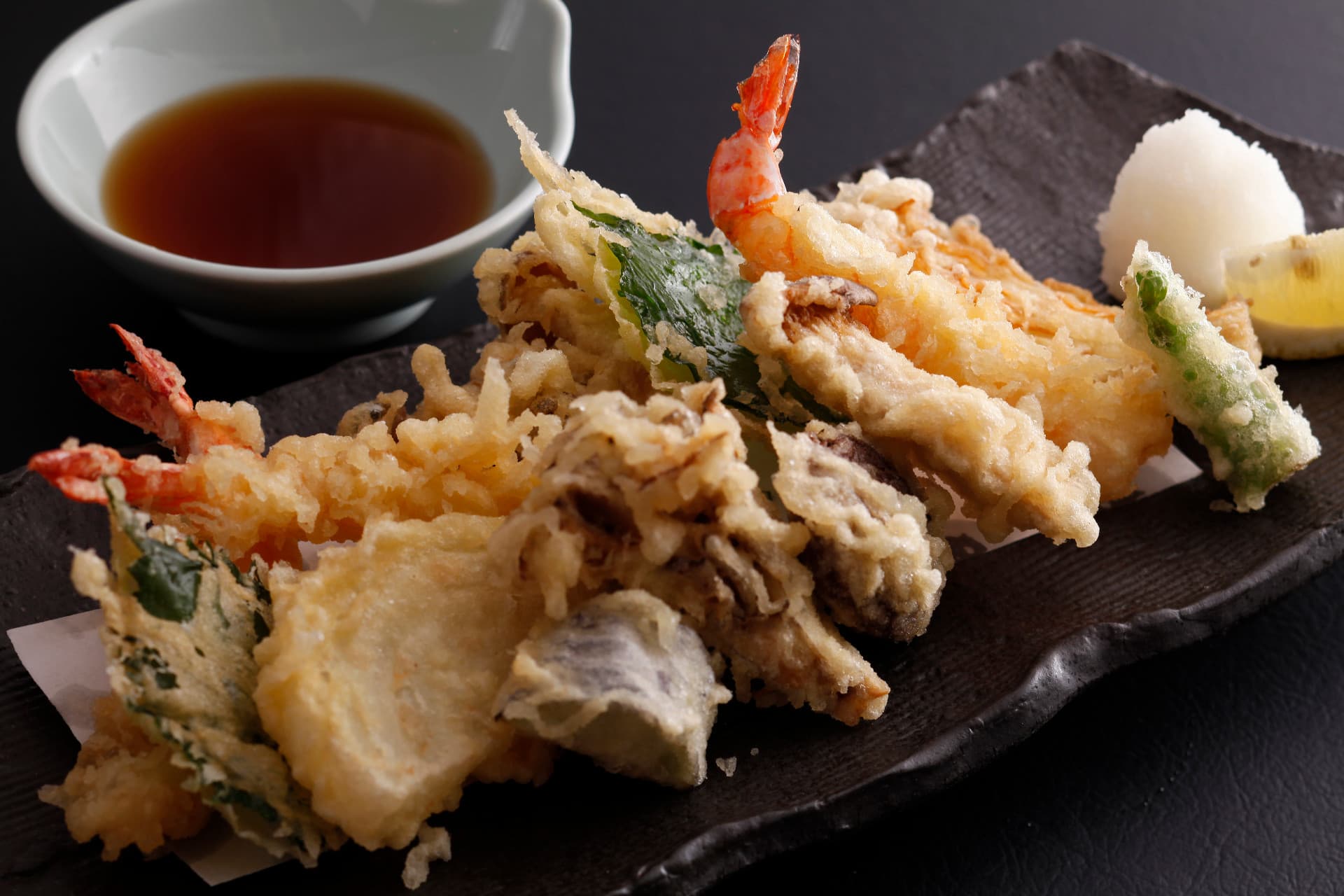 Freshly fried tempura of prawn and seasonal vegetables on a black slate plate at Miyukiso Hanamusubi