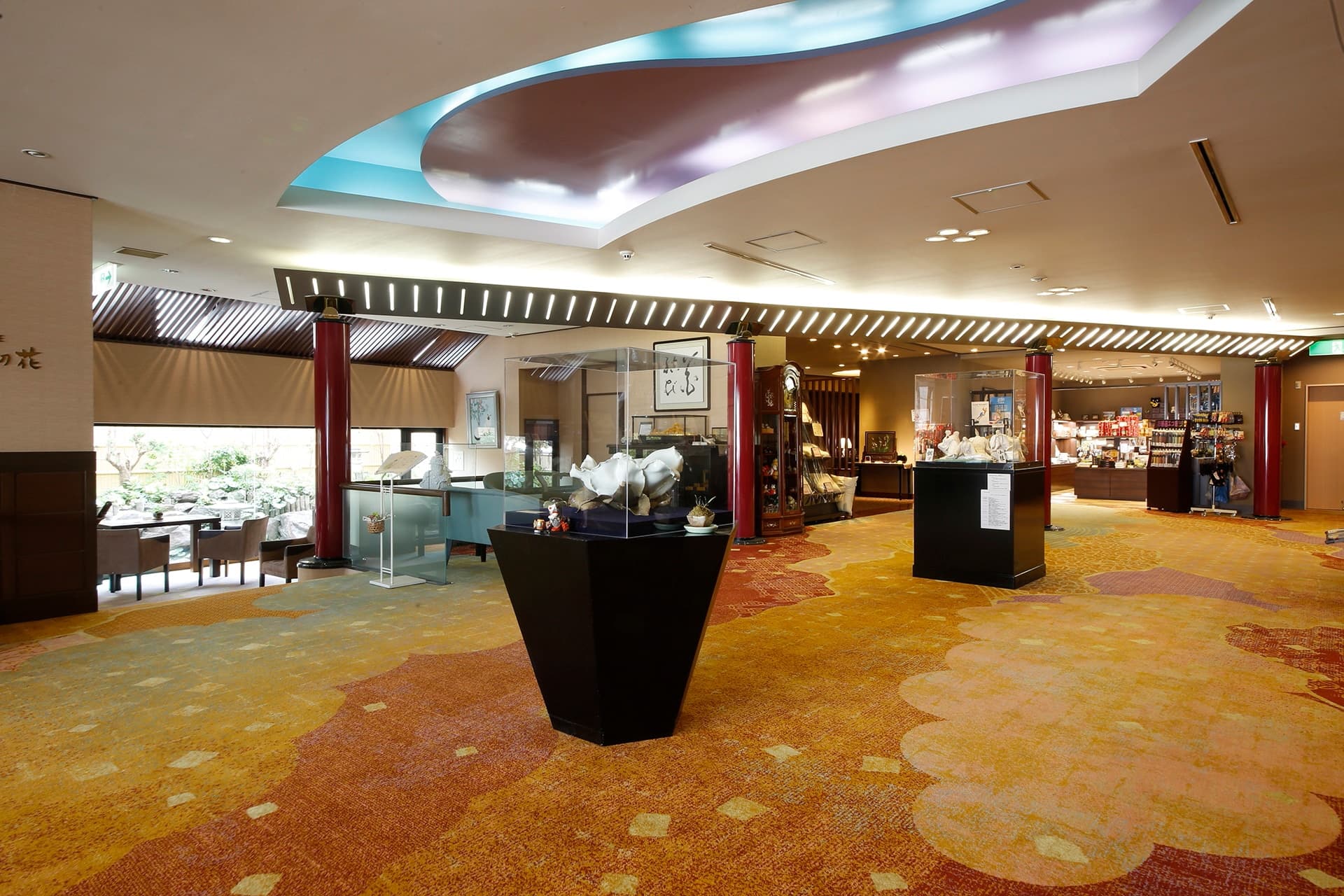 Lobby and gift-shop floor at Miyukiso Hanamusubi with flower-patterned carpet, red pillars and a garden view