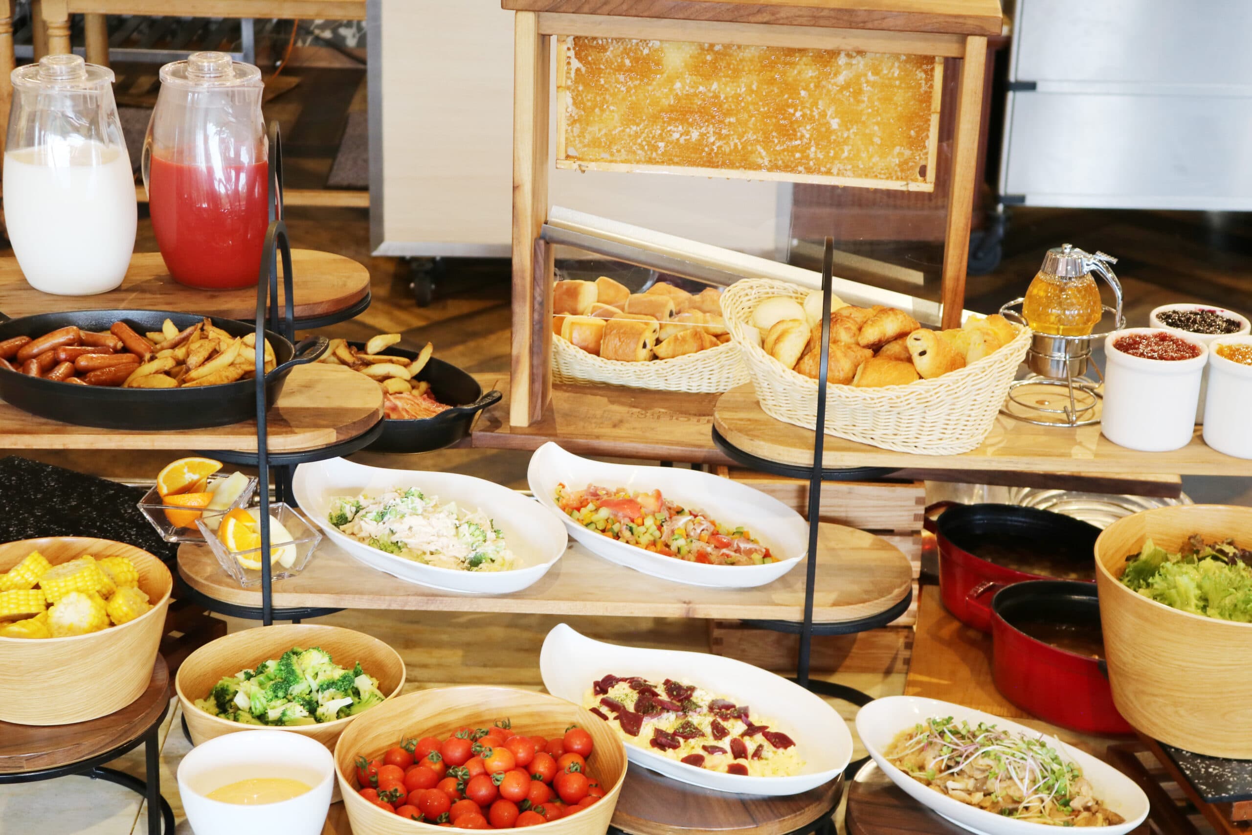 Breakfast buffet at Hotel Village with breads, sausages, salads and fresh tomatoes on tiered wooden stands