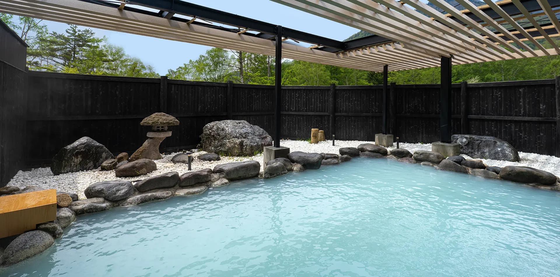 Milky-blue Yumoto sulphur hot spring open-air rotenburo with rock garden and slatted pergola