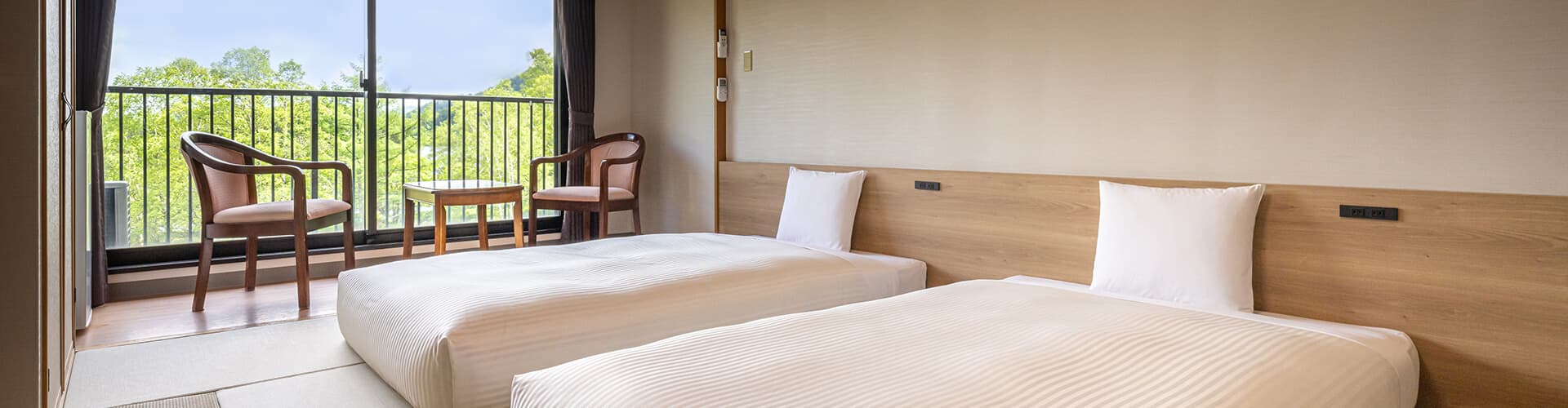 Bright twin guest room with tatami entry, wooden headboards and forest-view balcony at Kamenoi Hotel Okunikko-Yumoto