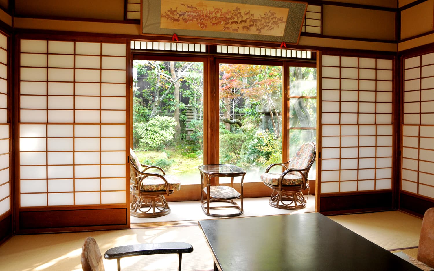 Tatami guest room at Kankaso ryokan in Nara with shoji screens, rattan chairs and a sunlit garden view through the window