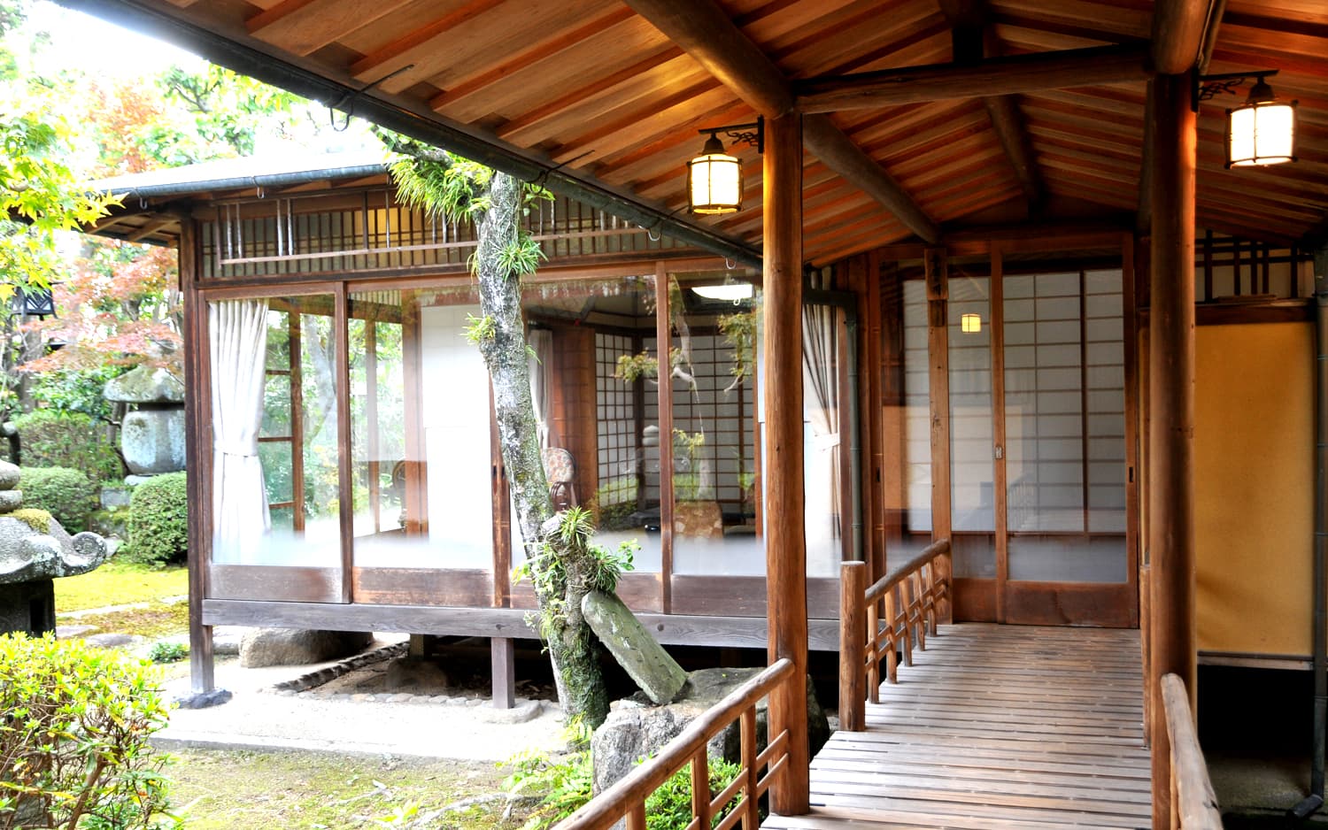 Wooden engawa veranda walkway at Kankaso ryokan in Nara lined with hanging lanterns overlooking a stone-and-moss garden