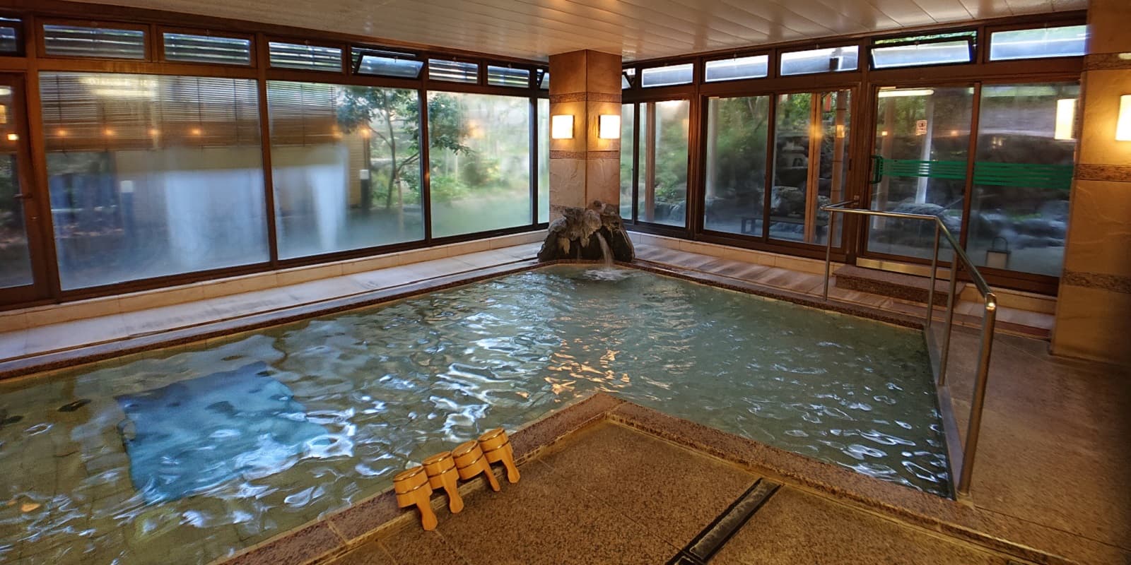 Spacious indoor uchiyu bath with garden-view windows and a stone fountain at Kasuga Hotel in Nara