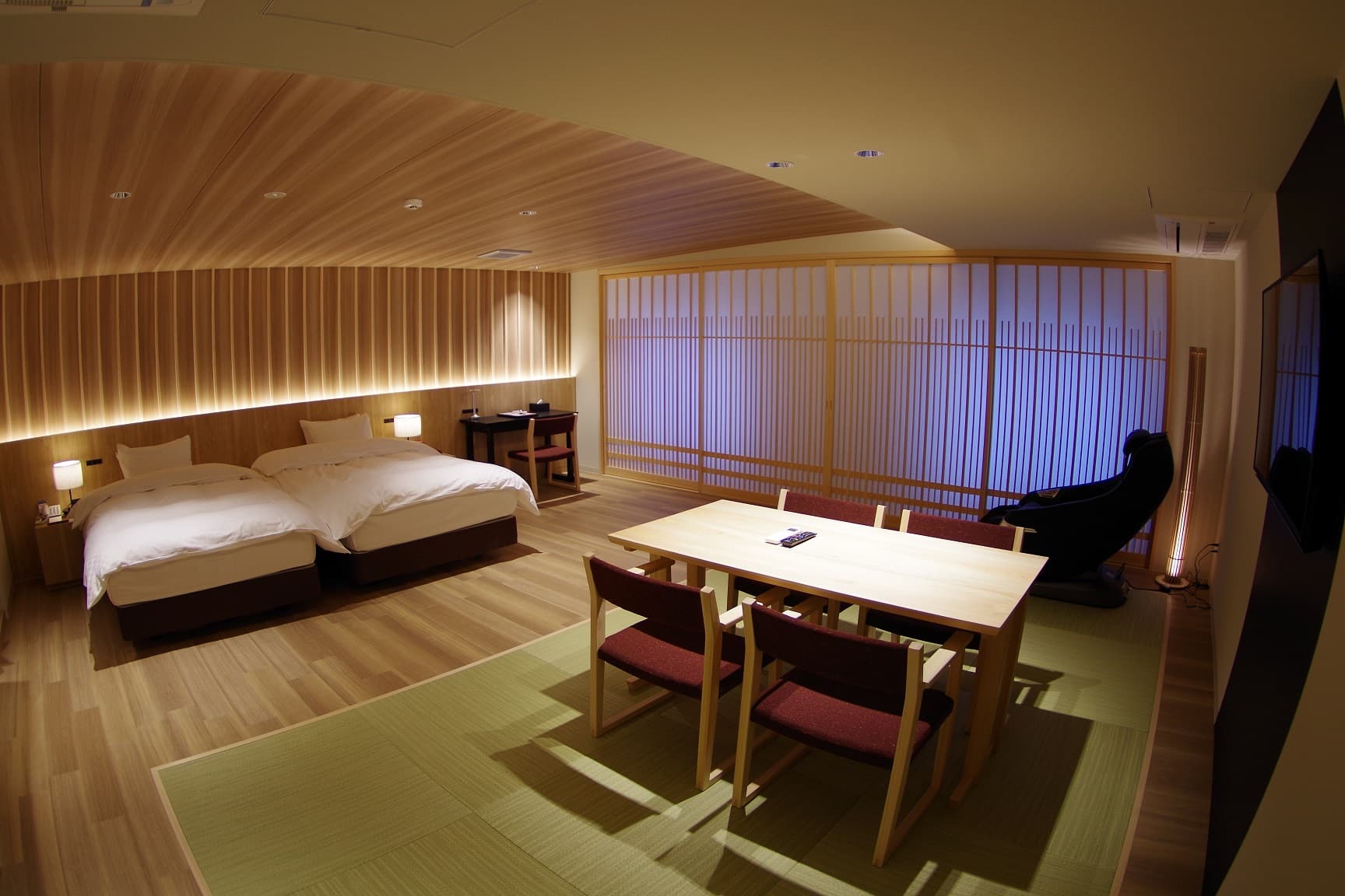 Spacious Japanese-modern guest room with twin beds, a tatami dining area and lattice screens at Kasuga Hotel
