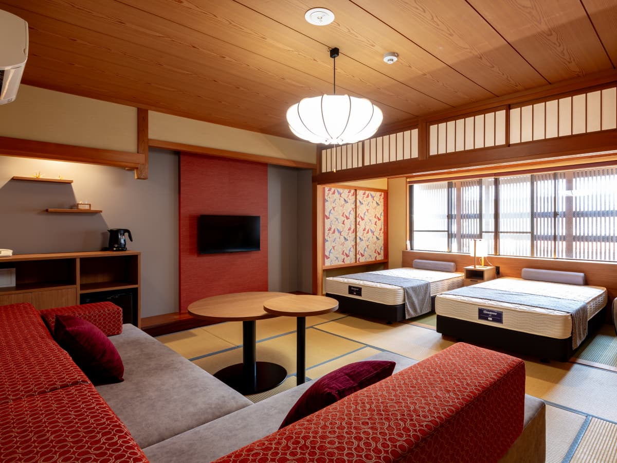 Spacious tatami twin room with crimson sofa and paper-lantern pendant light, Kawaguchiya Honkan, Kinosaki Onsen
