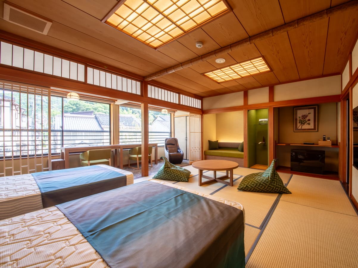 Bright tatami room with lounge chairs and townscape view through latticed windows, Kawaguchiya Honkan, Kinosaki Onsen