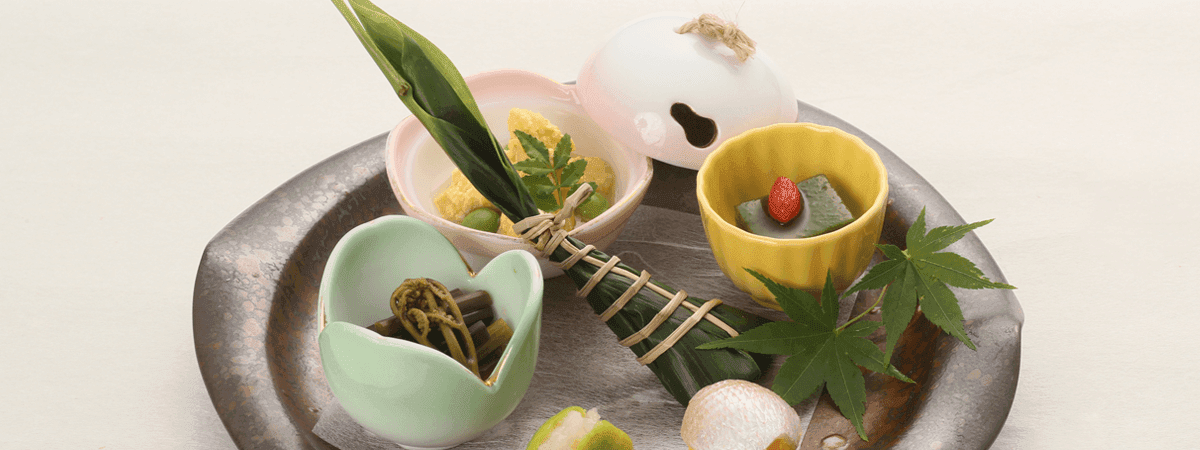 Seasonal kaiseki appetizer assortment plated on a dark ceramic dish with leaf garnish, Kawakamiya Kasuitei, Gero Onsen