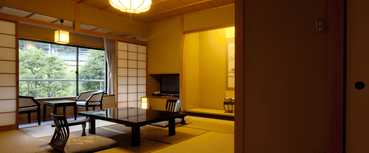 Traditional tatami guest room with hanging scroll, low dining table and chairs by a garden veranda, Kawakamiya Kasuitei, Gero Onsen