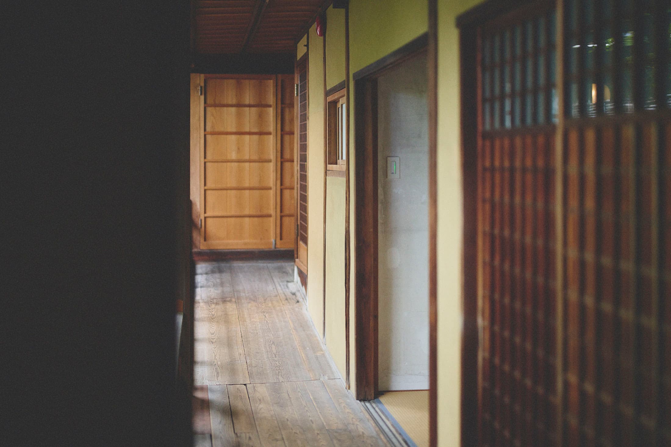 Sunlit wooden interior corridor at Kaze no Naramachi with lattice doors and tatami leading through the historic machiya