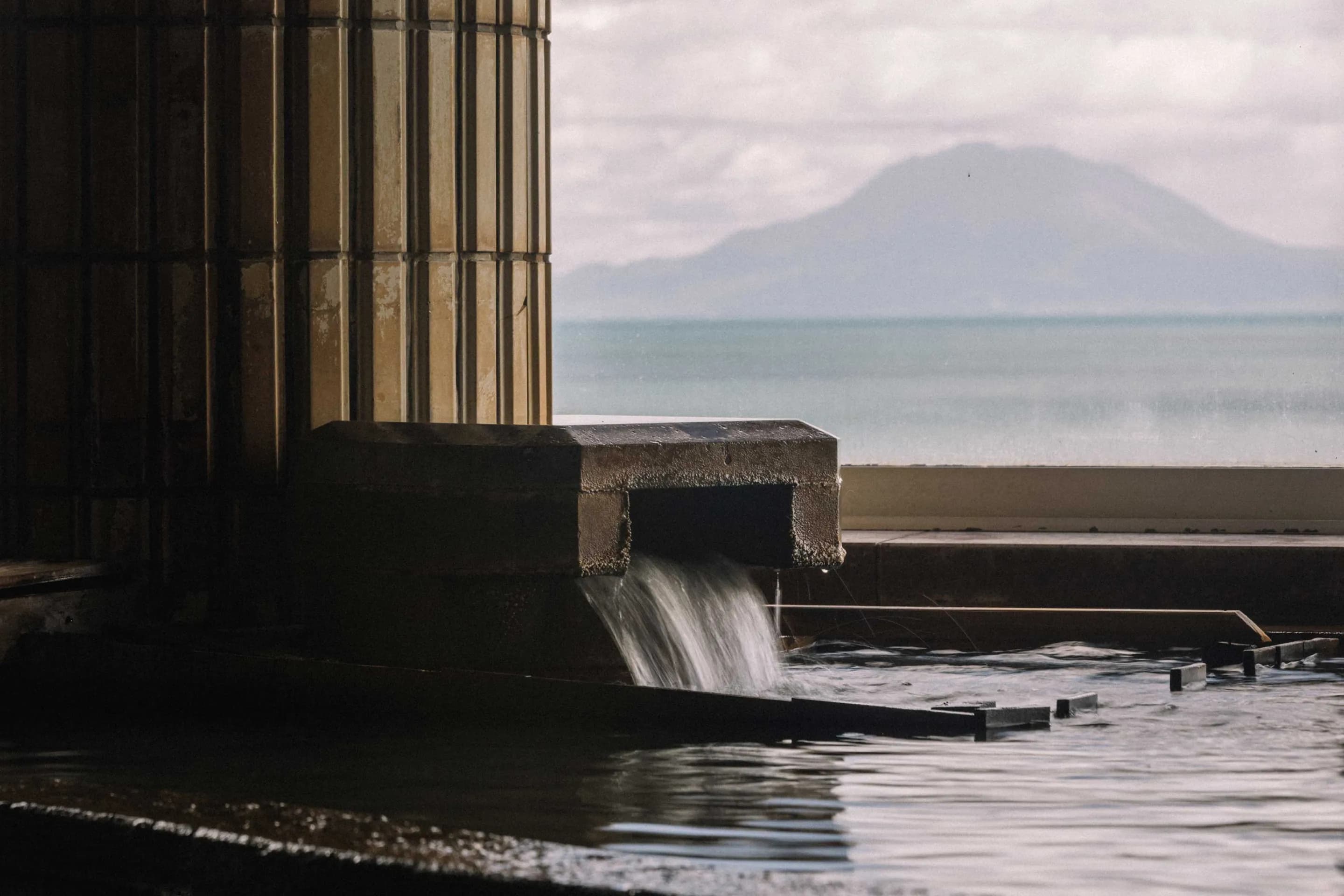 Open-air onsen bath at Koran no Yu Kinkouroh in Ibusuki overlooking Kinko Bay and the Sakurajima volcano