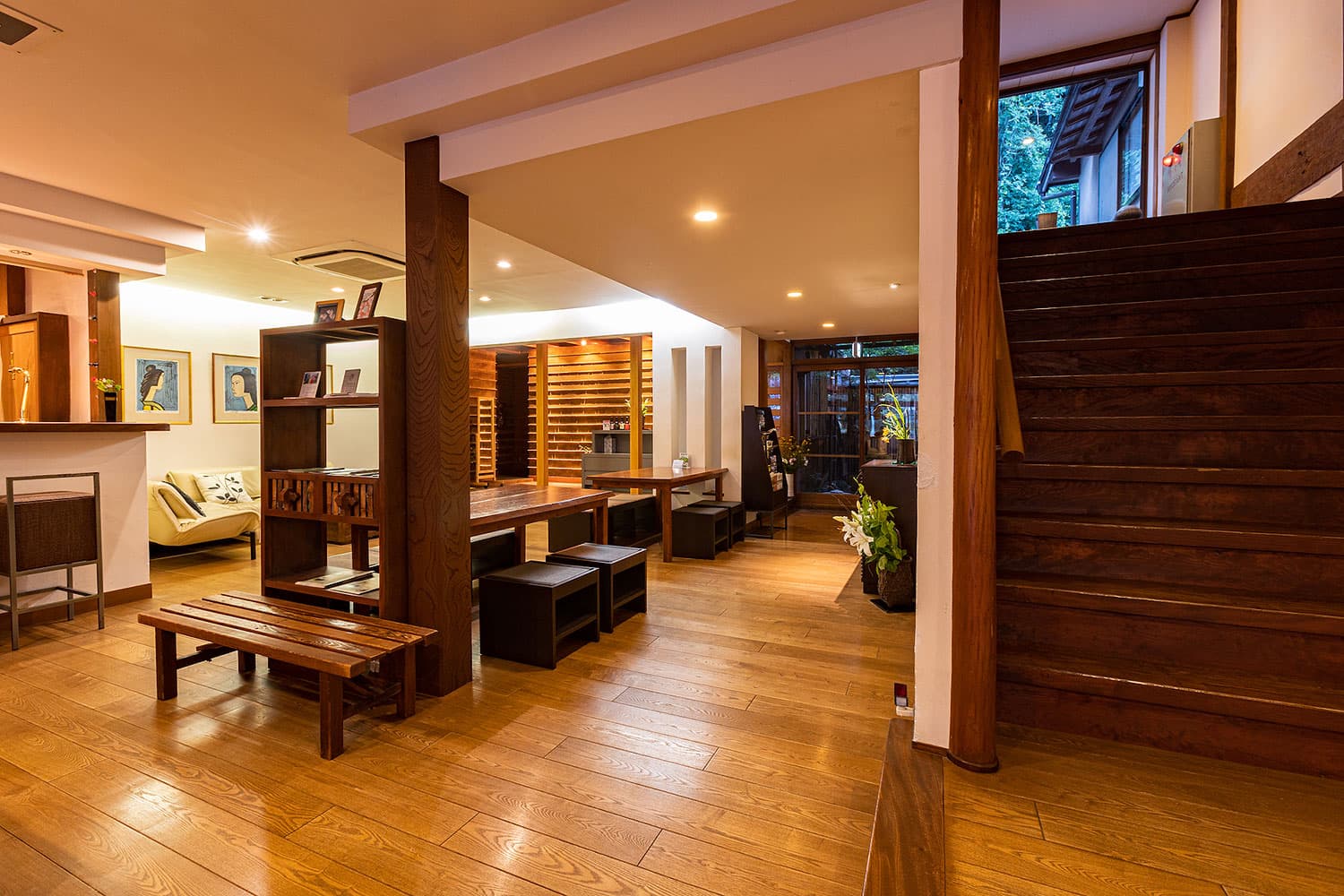 Warm wooden lobby lounge with seating and a staircase leading to upper floors, Yamamotoya, Kinosaki Onsen