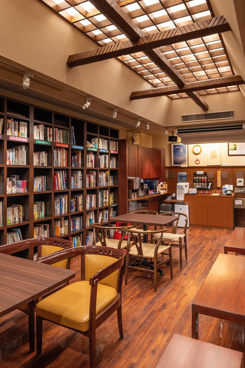 Book cafe lounge at Kinsuikan with tall bookshelves, lattice ceiling lights and reading tables