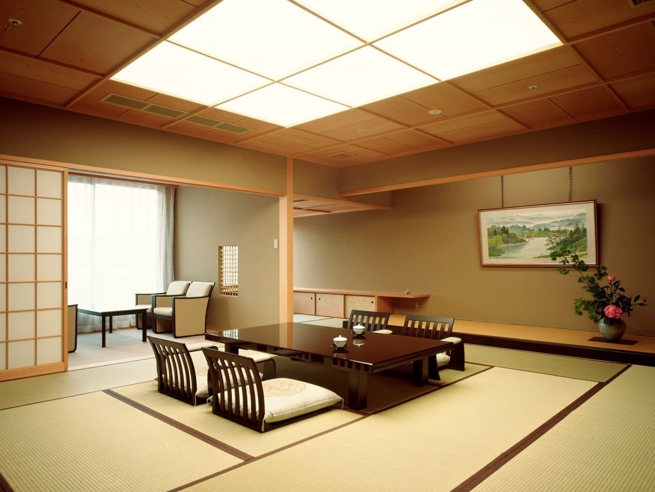 Spacious premium tatami guest room at Kinzan with floor seating, hanging scroll, flower arrangement and a window lounge area