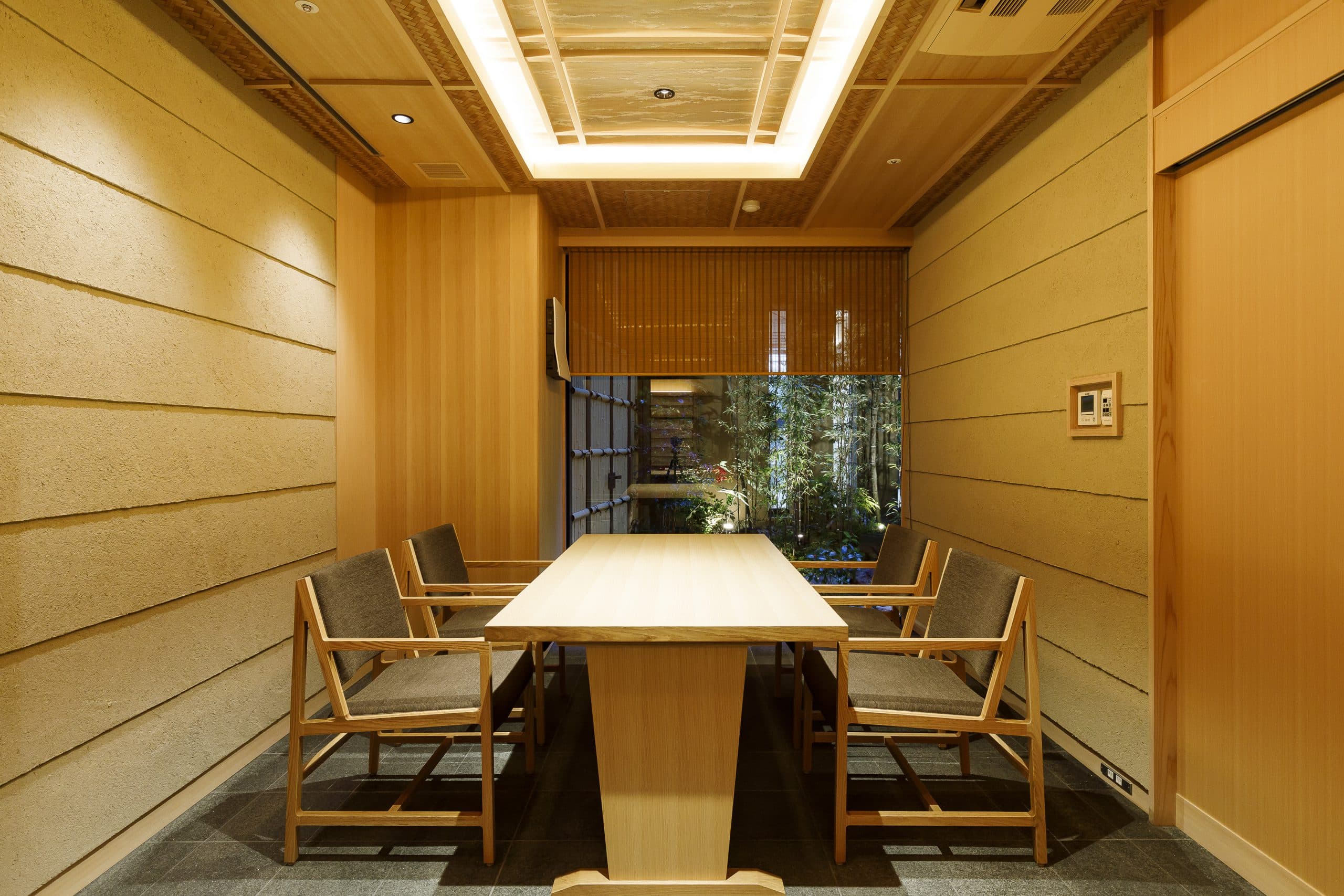Private dining room at Kinzan finished in warm cedar with a long wooden table, woven chairs and a small interior garden window