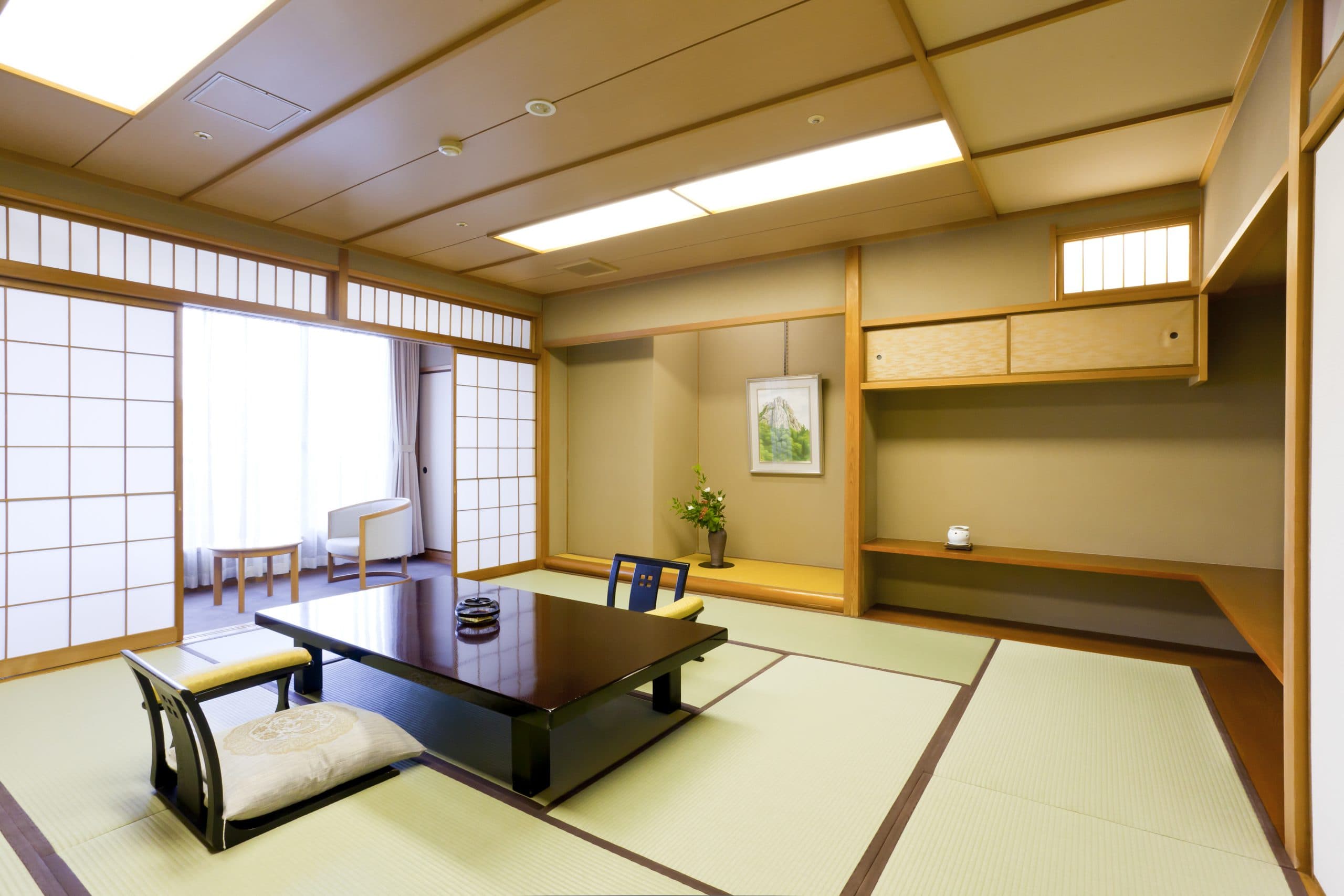 Traditional tatami guest room at Kinzan with low table, framed landscape scroll and shoji windows letting in soft daylight