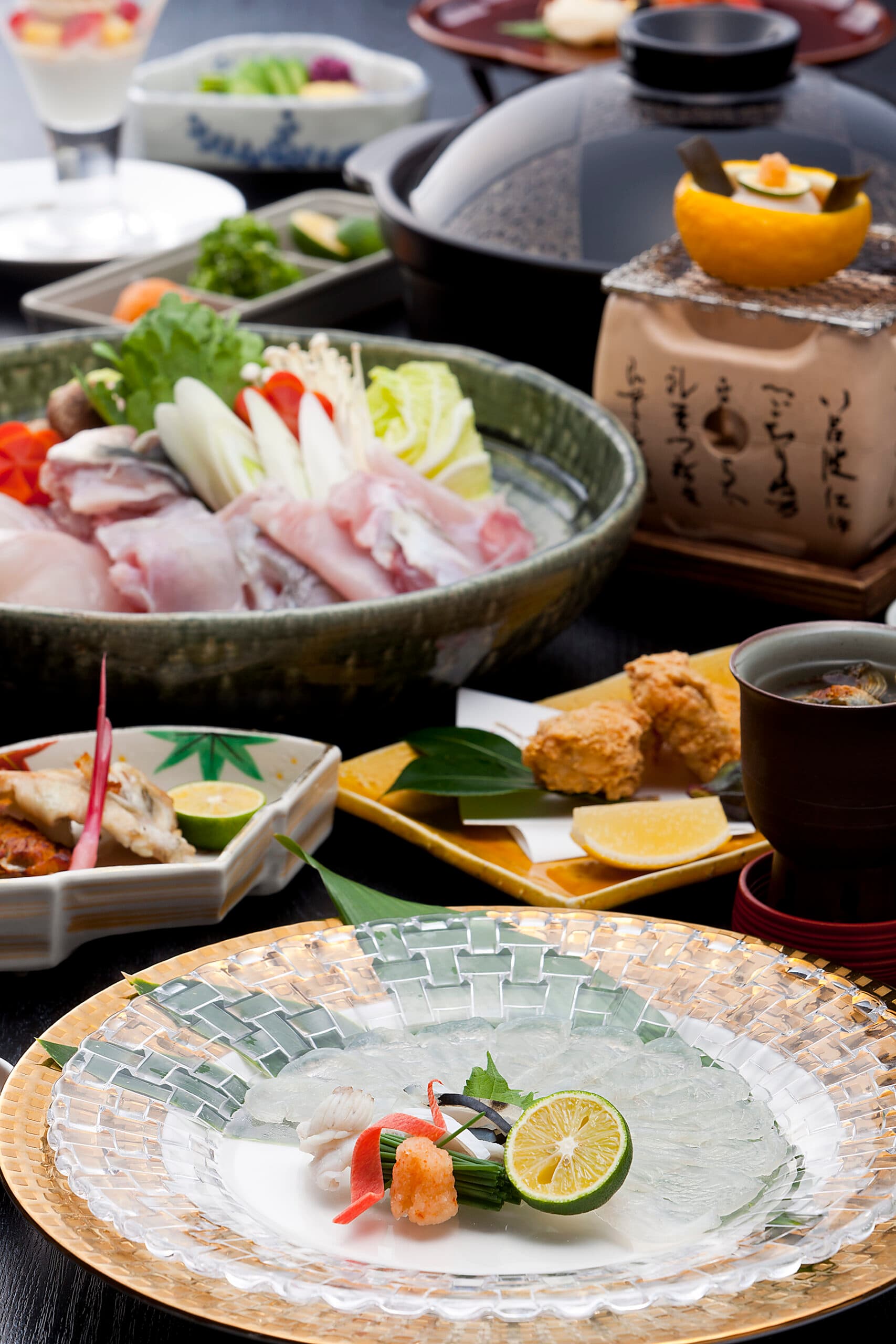 Kaiseki dinner course at Kinzan featuring a seafood and vegetable hot pot, tempura and assorted small dishes on dark tableware