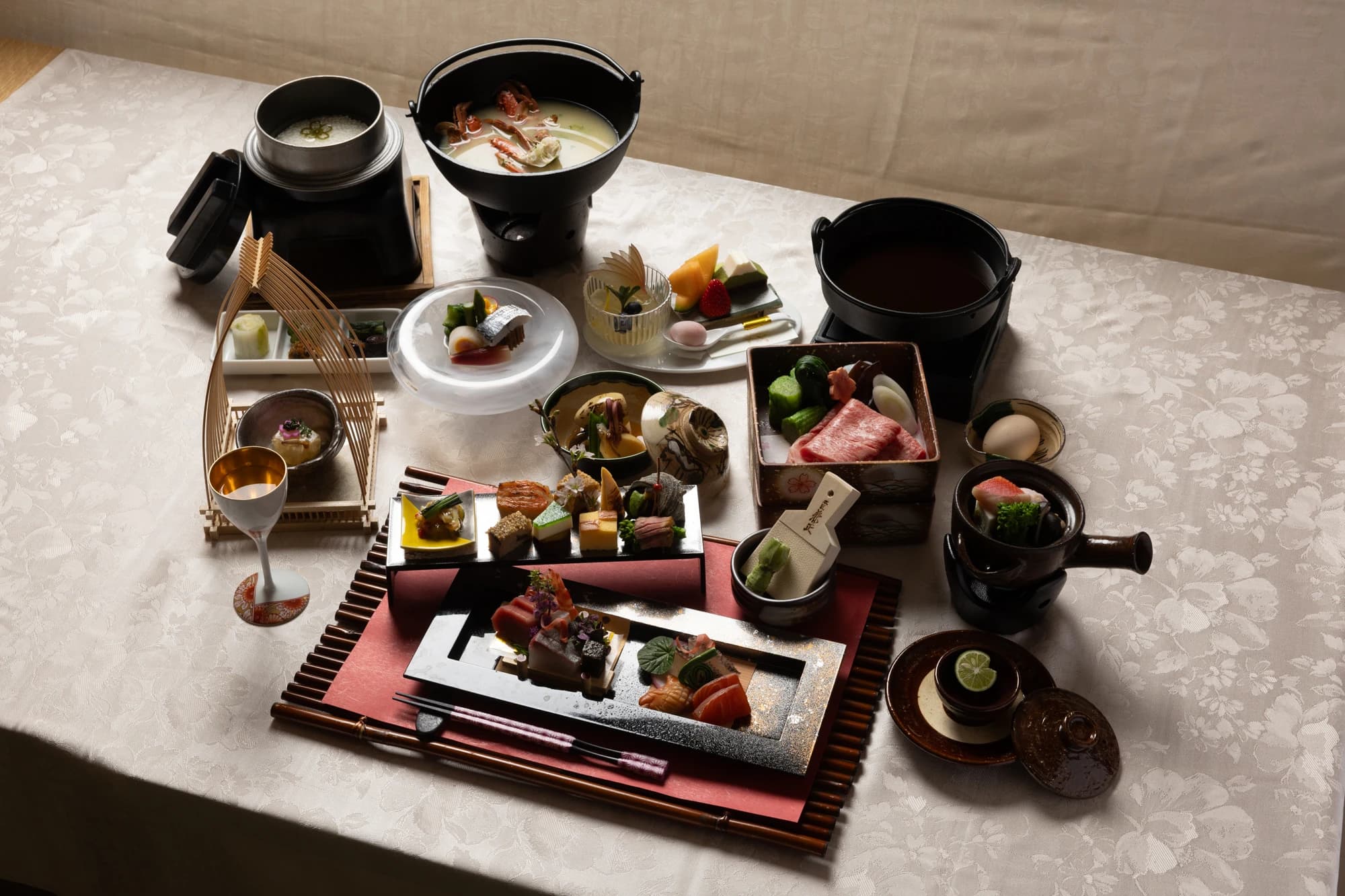 Multi-course kaiseki dinner spread at Konansou with sashimi, simmered dishes, and a hot pot on a white tablecloth