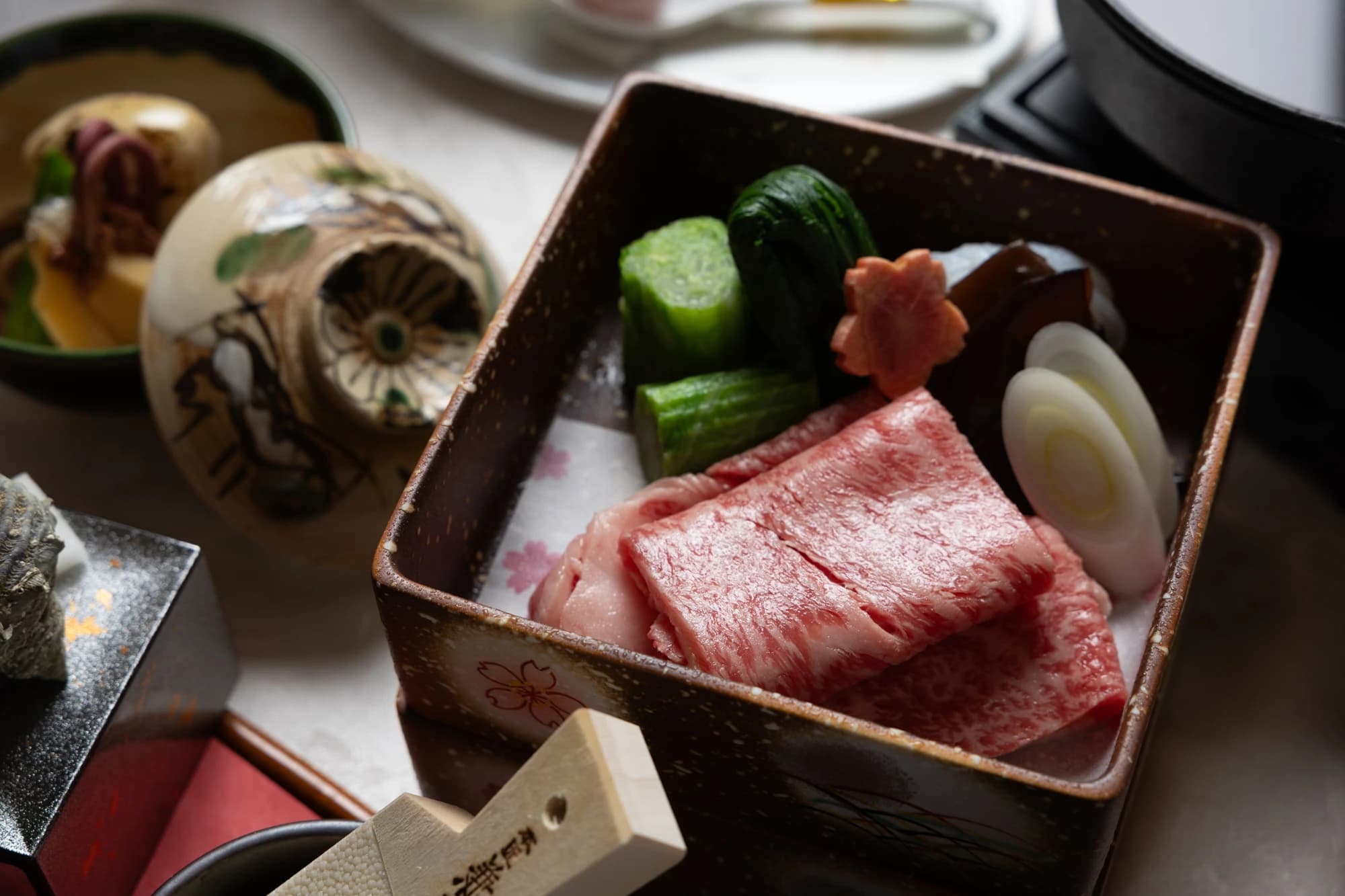 Close-up of a marbled wagyu beef hot-pot course at Konansou served with seasonal vegetables in a ceramic box