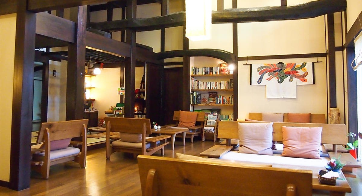 Cozy timber-beamed lounge with wooden sofas, cushions and a library shelf at Oyado Koto no Yume, Takayama